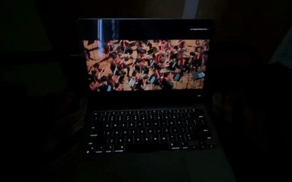 A MacBook in a dark room with its keyboard backlight lit